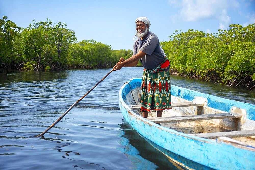 Fisher boat in Makanda Channel, Lamu archipelago, Kenya. Red mangroves along coastline of Manda Island