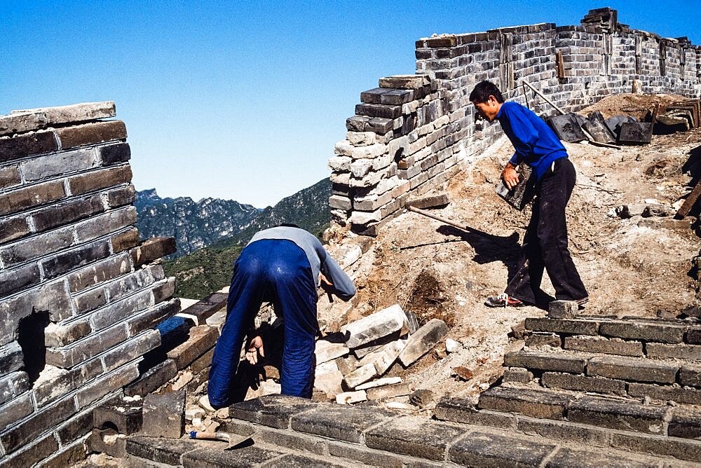 Two Chinese men working on the restoration of the Great Wall at Mutianyu, China.