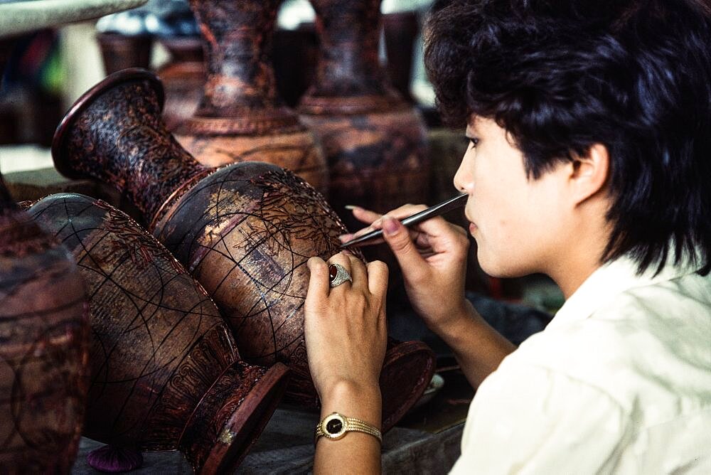 An artisan attaches cloisons or wire strip to make the design for a cloissone vase in a workshop in Beijing, China.