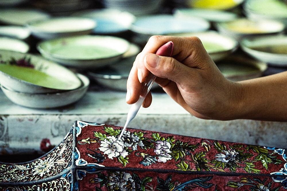 An artisan applies enamel frit with an eyedropper on a cloissone vase in a workshop in Beijing, China.