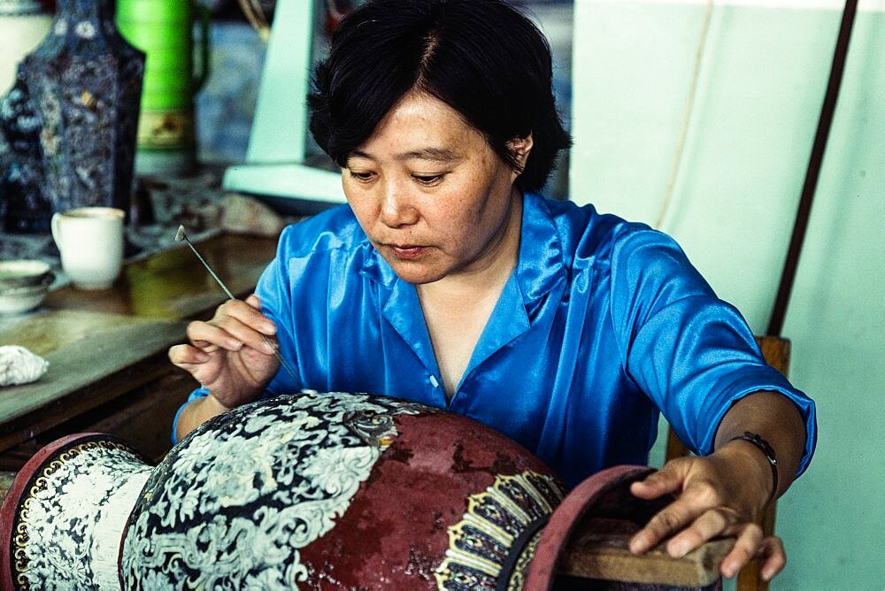 An artisan works on a cloissone vase before the first firing in a workshop in Beijing, China.