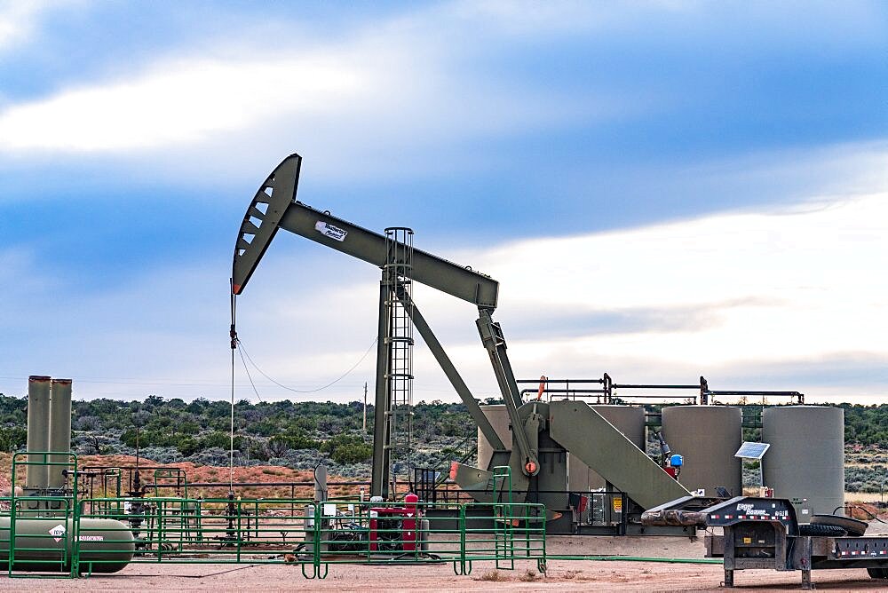 A conventional horsehead oil well pump jack unit and storage tank battery on an oil well site in Utah.