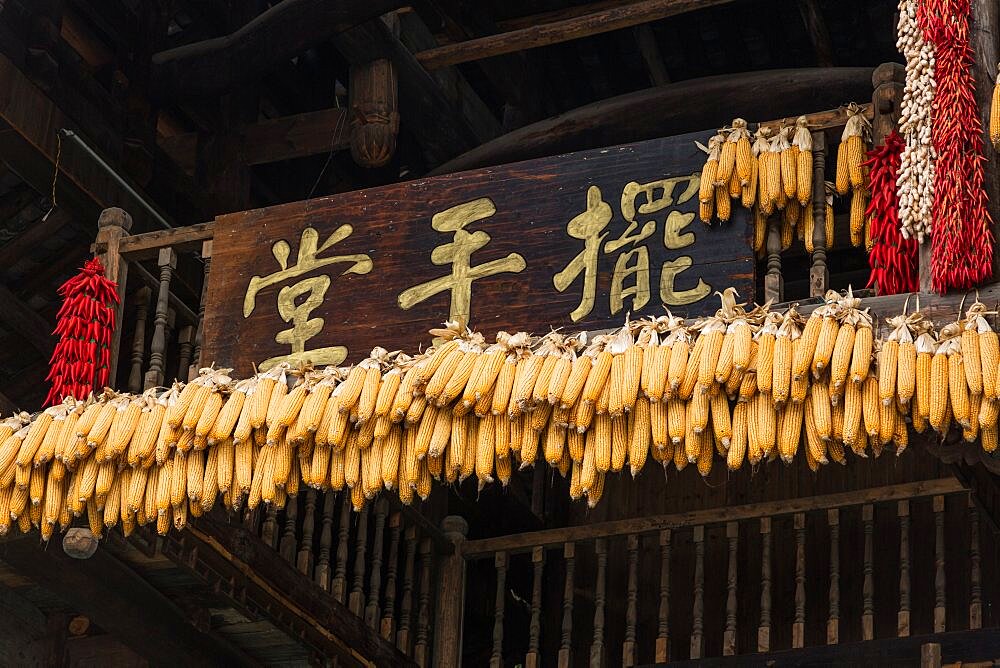 Strands of dried chili peppers and ears of corn over the doorway to a shop in Furong, China.