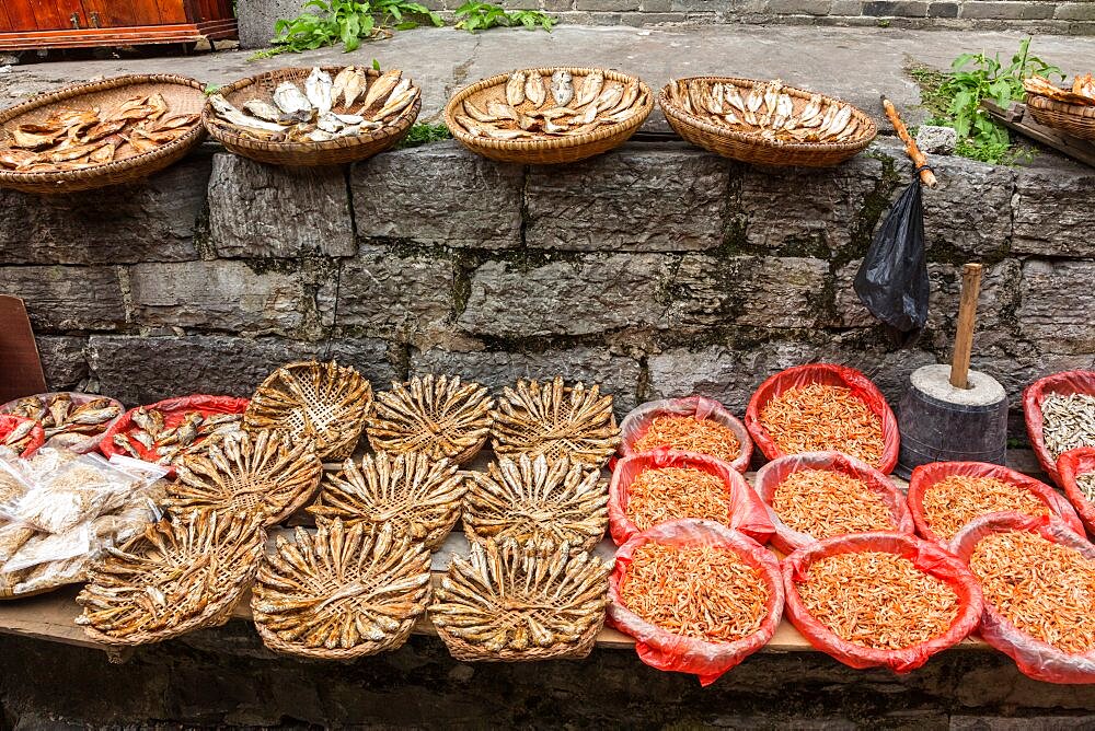 Baskets of dried fish and shrimp for sale on the street in the ancient town of Furong, China.