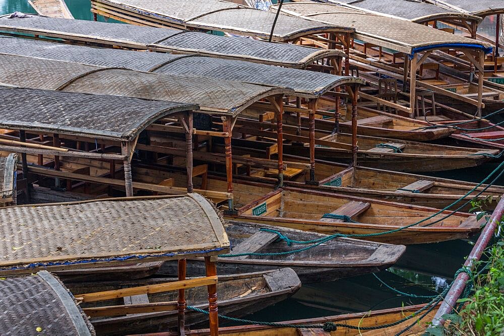 A cluster of covered tour boats tied up on the bank of the Tuojiang River in Fenghuang, China.