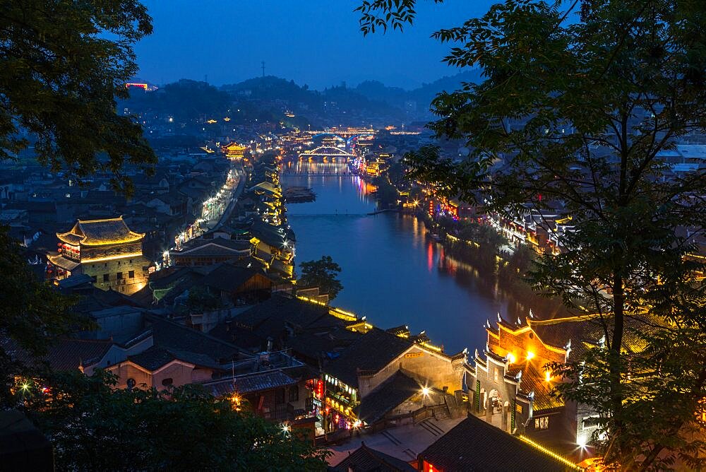 Bridges over the Tuojiang River lit up at night in Fenghuang, China.