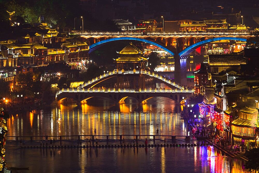 The Fenghuang Bridge and highway bridge over the Tuojiang River, lit at night. Fenghuang, China.