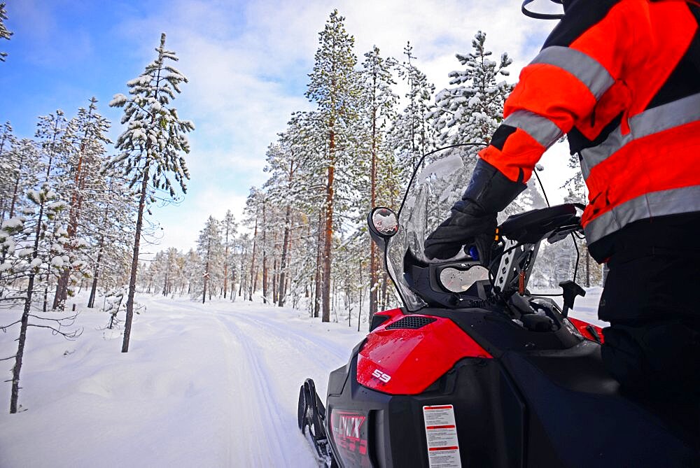 Antti, young Finnish guide from VisitInari, rides a snowmobile in the wilderness of Inari, Lapland, Finland