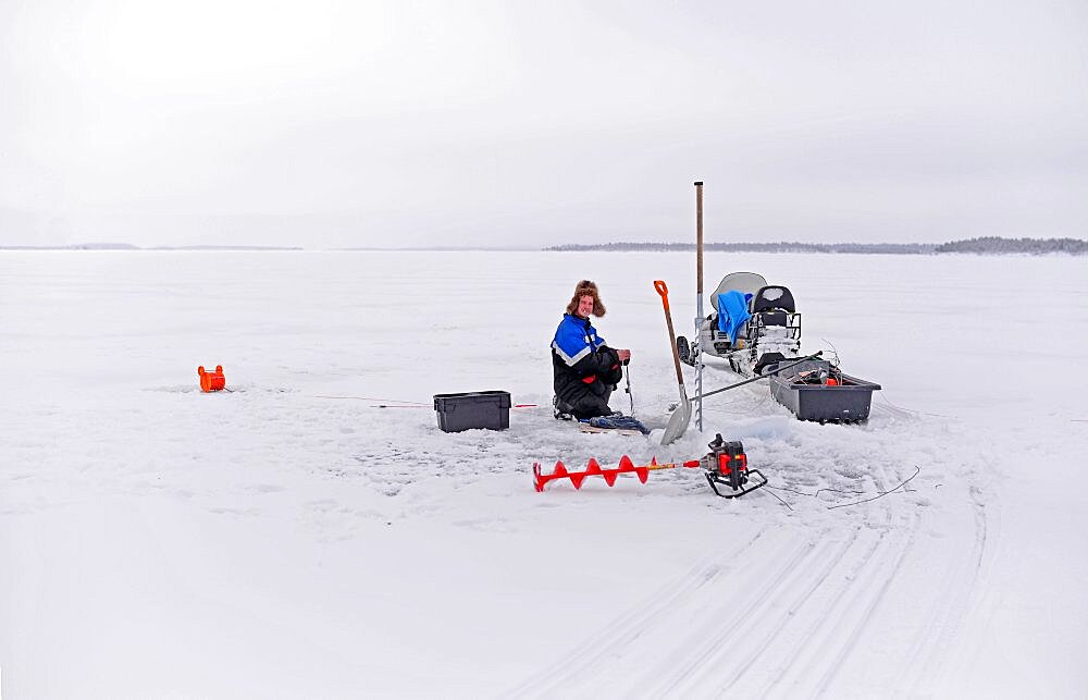 Fisherman practicing ice fishing in Lake Inari, Lapland, Finland