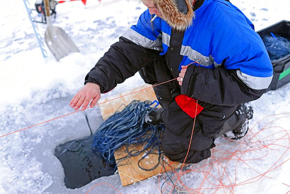 Fisherman practicing ice fishing in Lake Inari, Lapland, Finland