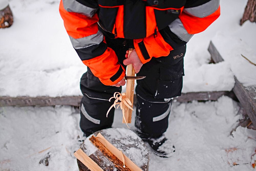 Antti, young guide from VisitInari, prepares a fire in the wilderness of Lake Inari, Lapland, Finland