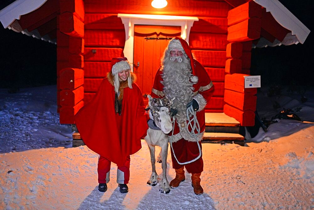 Santa Claus poses with Elf and Reindeer. Santa¥s Home in Kakslauttanen Arctic Resort. Lapland, Finland