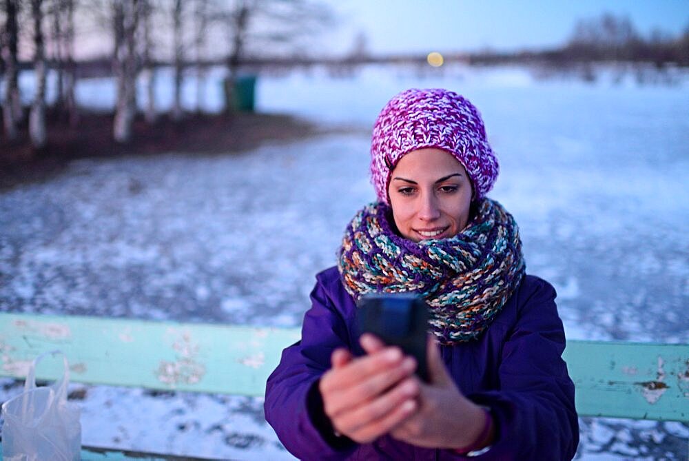 Young woman using mobile telephone in winter environment