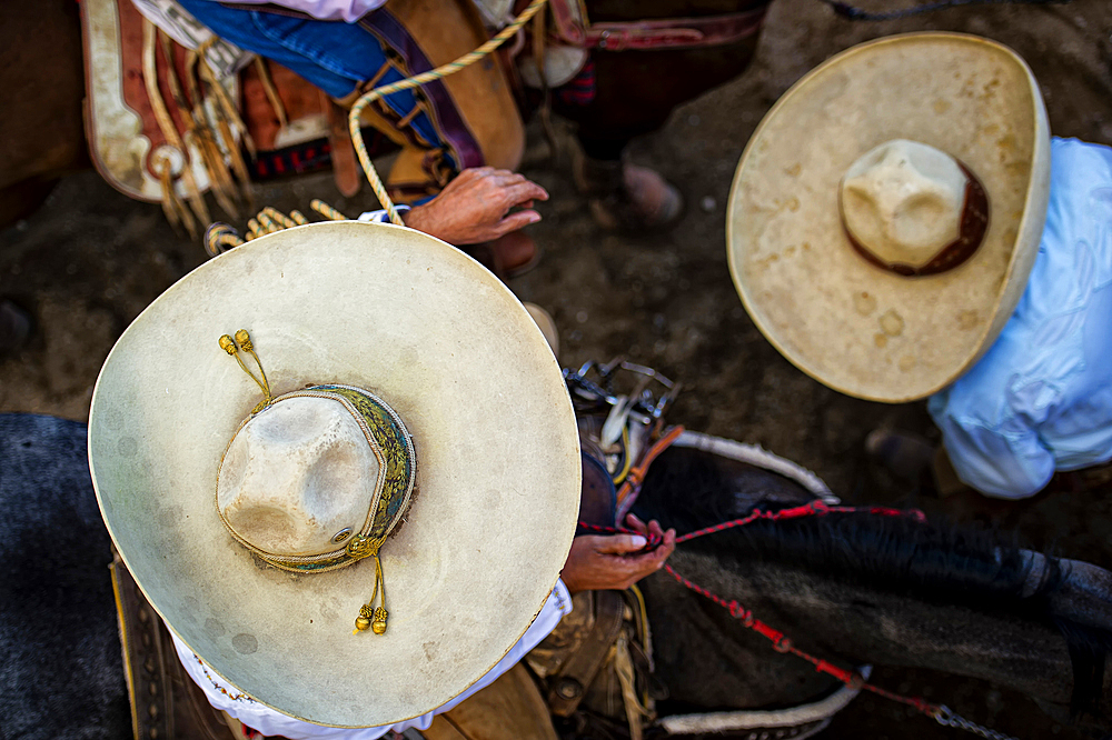 The participants in the charreada wear traditional charro clothing, including a closely fitted suit, chaps, boots, and a wide brim sombrero,