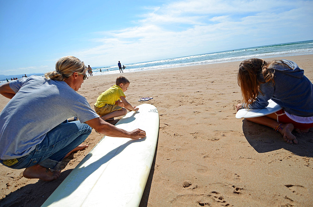 Surfers prepare their boards on Cote des Basques beach at sunset, Biarritz