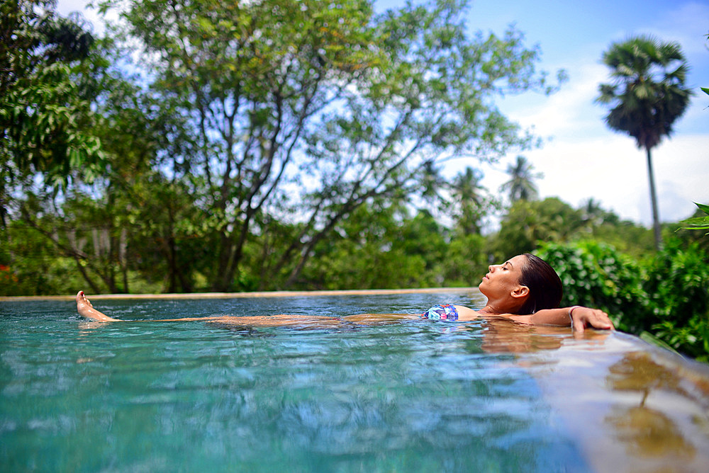 Young attractive woman enjoying a bath in the infinity edge swimming pool at The Dutch House, Galle, Sri Lanka