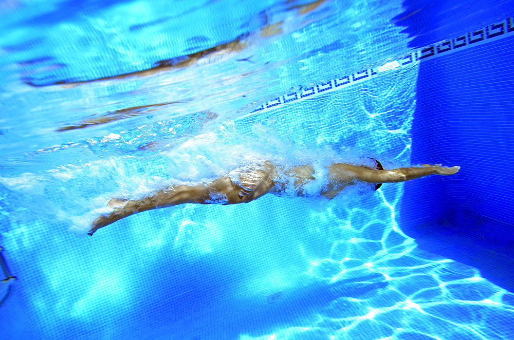 Young woman dives into swimming pool