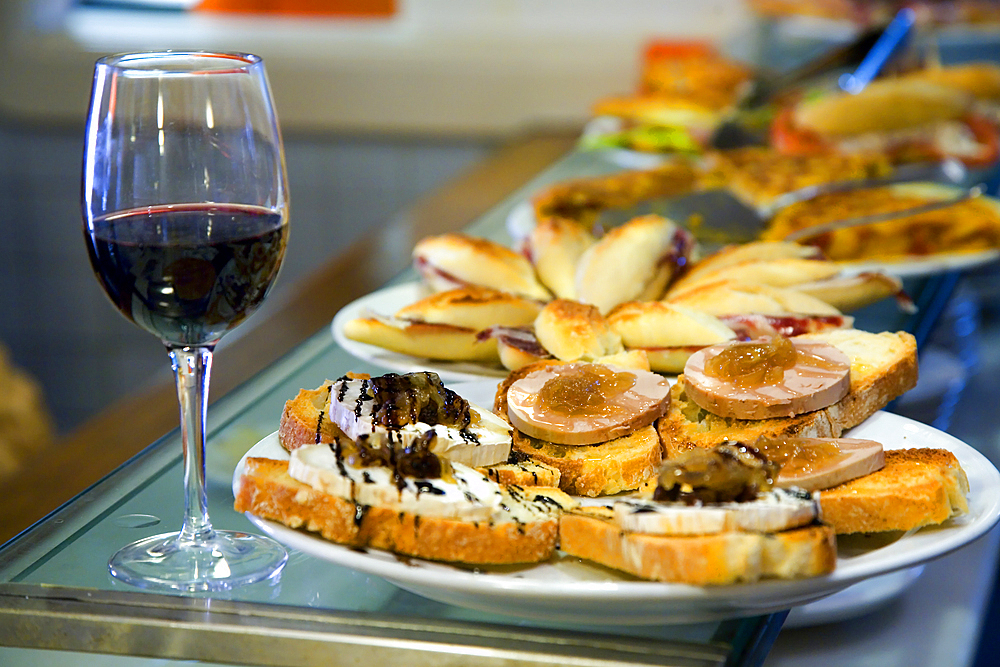 Small portions of food or tapas and a wine glass in a restaurant.