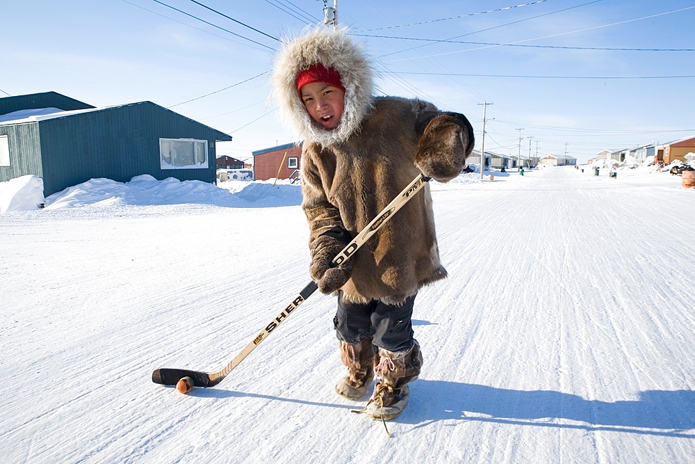 Young boy plays ice hockey in the streets of Gojahaven, an Inuit settlement in the far north of Canada.