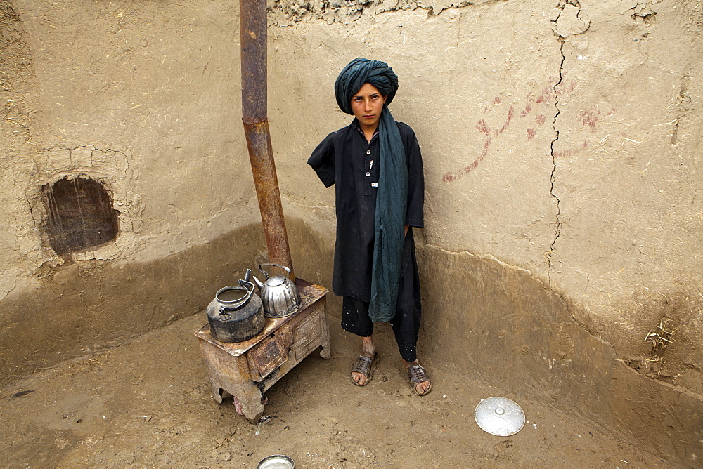 Afghan boy in front of a stove