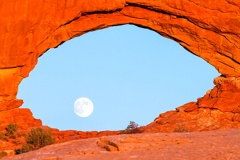 Moon rising in the North Window, an Entrada sandstone arch in the WIndows Section of Arches National Park, Moab, Utah.