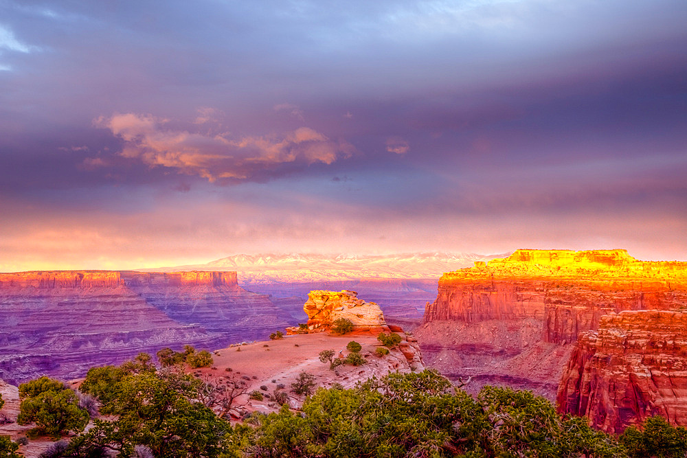 Sunset light on the Shafer Canyon Overlook in the Island in the Sky District, Canyonlands National Park, Utah. Dead Horse Point at left with the La Sal Mountains behind.