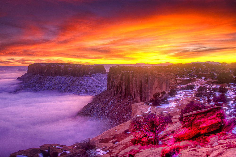 Colorful sunset over Junction Butte and Grandview Point with a sea of clouds below. Canyonlands National Park, Utah.