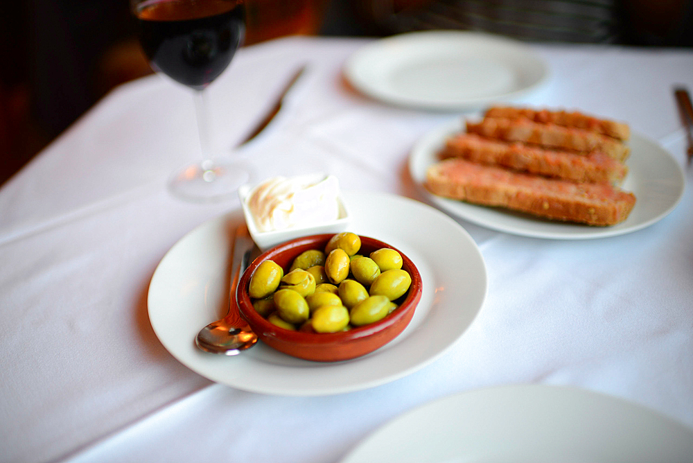 Green olives, bread and alioli on restaurant table, Mallorca