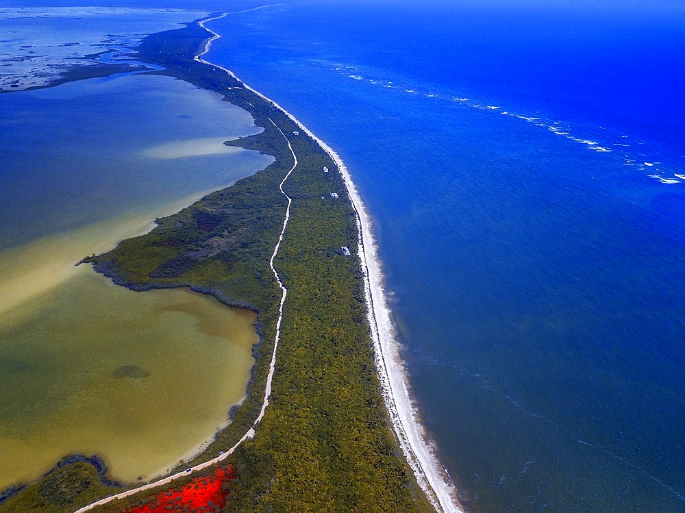 Aerial view of Punta Allen Sian Ka'an Reserve, Yucatan Peninsula, Mexico. Red lagoon near Boca Paila Bridge.

In the language of the Mayan peoples who once inhabited this region, Sian Ka'an means Origin of the Sky. Located on the east coast of the Yucatán peninsula, this biosphere reserve contains tropical forests, mangroves and marshes, as well as a large marine section intersected by a barrier reef. It provides a habitat for a remarkably rich flora and a fauna comprising more than 300 species of birds, as well as a large number of the region's characteristic terrestrial vertebrates, which cohabit in the diverse environment formed by its complex hydrological system.

Along its roughly 120 kilometres of coastline, the property covers over 400,000 hectares of land ranging from sea level to only ten m.a.s.l. The property boasts diverse tropical forests, palm savannah, one of the most pristine wetlands in the region, lagoons, extensive mangrove stands, as well as sandy beaches and dunes. The 120,000 hectares of marine area protect a valuable part of the Mesoamerican Barrier Reef and seagrass beds in the shallow bays. The lush green of the forests and the many shades of blue of the lagoons and the Caribbean Sea under a wide sky offer fascinating visual impressions.