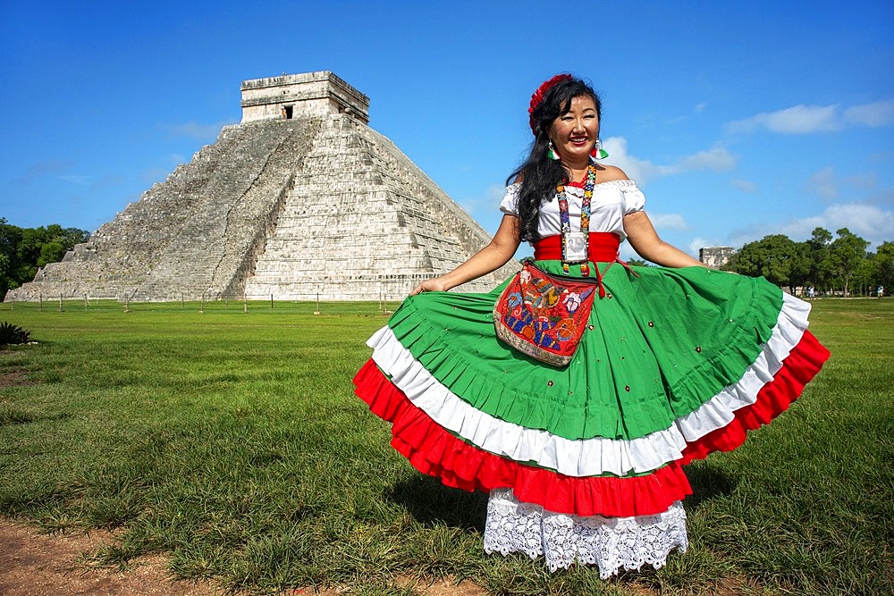 El Castillo, The Pyramid of Kukulkán, is the Most Popular Building in the UNESCO Mayan Ruin of Chichen Itza Archaeological Site Yucatan Peninsula, Quintana Roo, Caribbean Coast, Mexico. Asian tour leder dressed in a maya style.