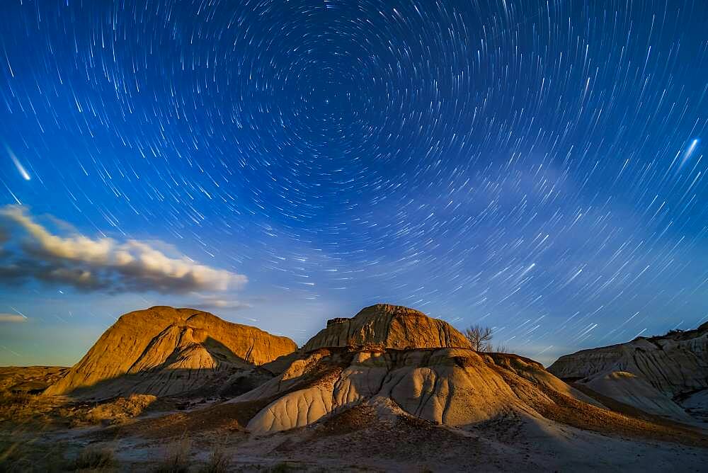 The eroding formations of Dinosaur Provincial Park, Alberta, lit by the rising gibbous Moon, off camera at right, on April 21/22, 2019. This is looking north, with the stars of the northern sky pivoting around Polaris.