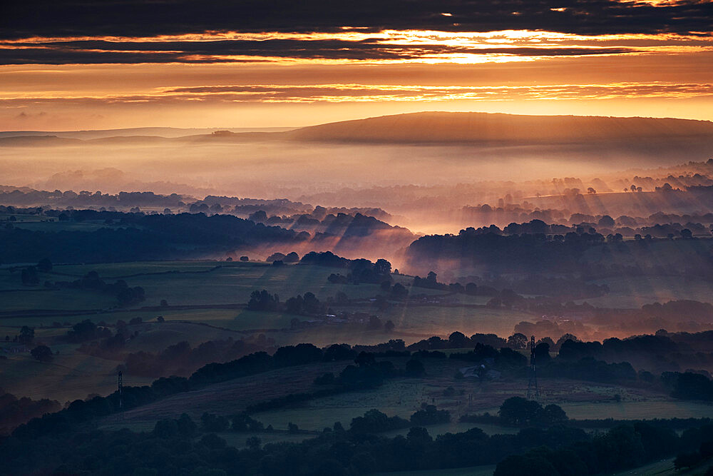 Morning sunbeams and early morning fog cover the Cheshire Plain at sunrise, from Bosley Cloud, Cheshire, England, United Kingdom, Europe