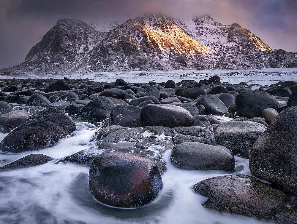 Boulders on Uttakleiv Beach backed by Himmeltinden Mountain in winter, Vestvagoya Island, Lofoten Islands, Norway, Scandinavia, Europe