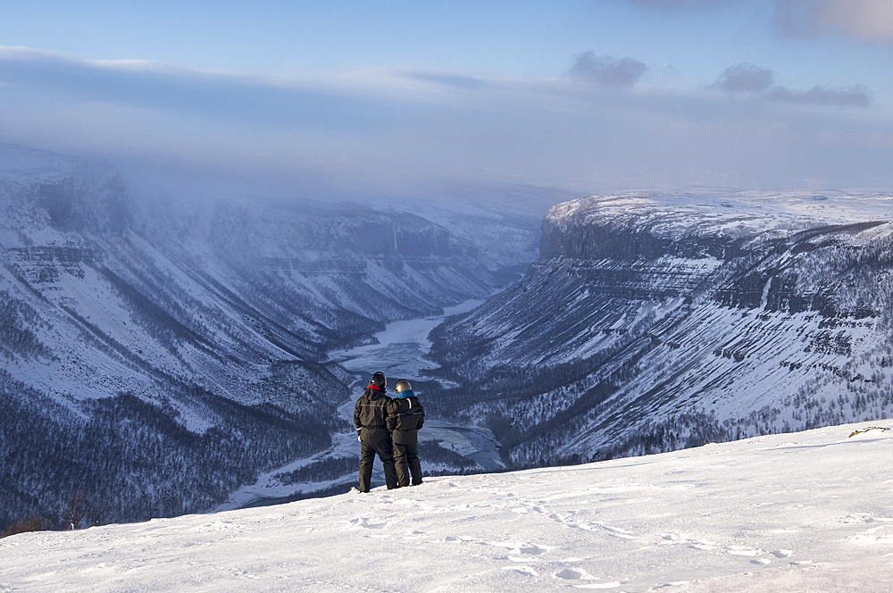 Couple in Snowsuits looking out over the Alta Canyon and Alta River from the Finnmark Plateau in winter, Finnmark Plateau, near Alta, Norway, Arctic Circle, Scandinavia, Europe