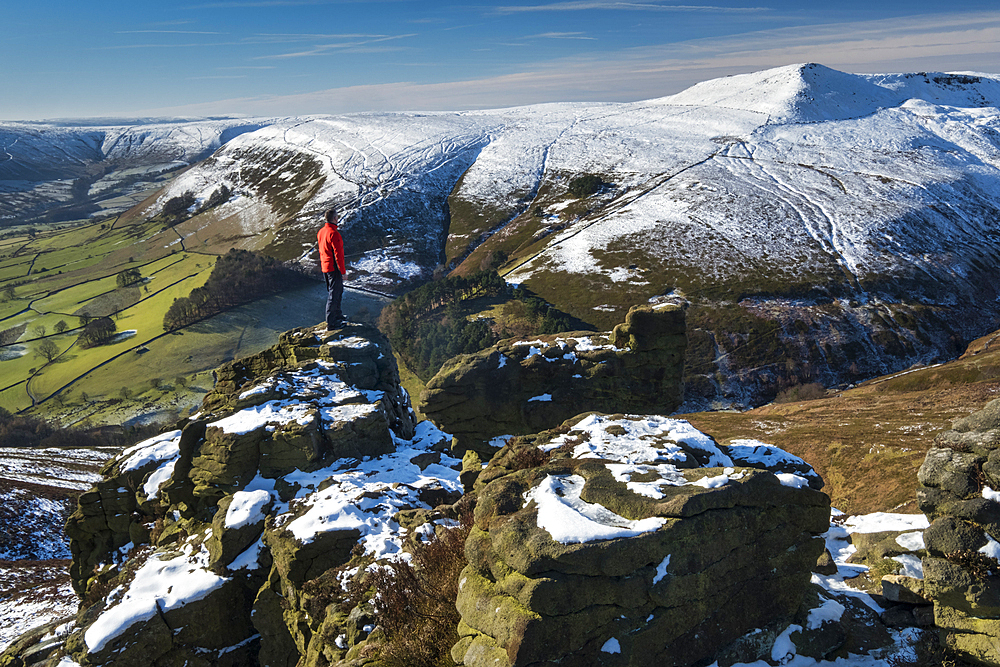 Walker looks out over Grindslow Knoll and the Edale Valley from Ringing Roger rock formation in winter, Kinder Scout, Peak District National Park, Derbyshire, England, United Kingdom, Europe