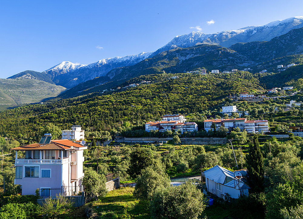 Snow capped peaks including Mount Cika rising above hillside village, Palase, near Dhermi, Albania, Europe