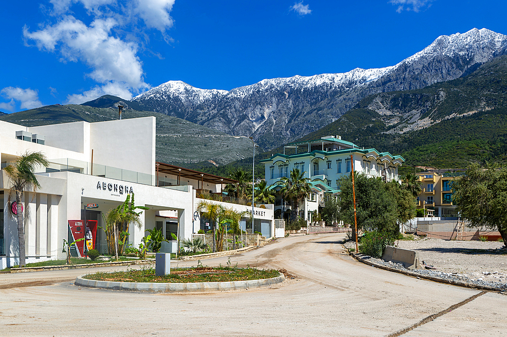 Tourist development construction building work view from Drymades Beach to Mount Cika snow capped mountain range, Dhermi, Albanian Riviera, Albania, Europe