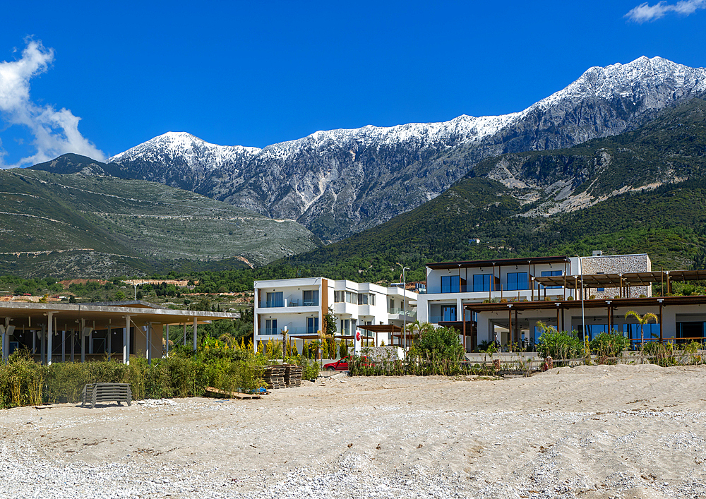 Tourist development construction building work view from Drymades Beach to Mount Cika snow capped mountain range, Dhermi, Albanian Riviera, Albania, Europe