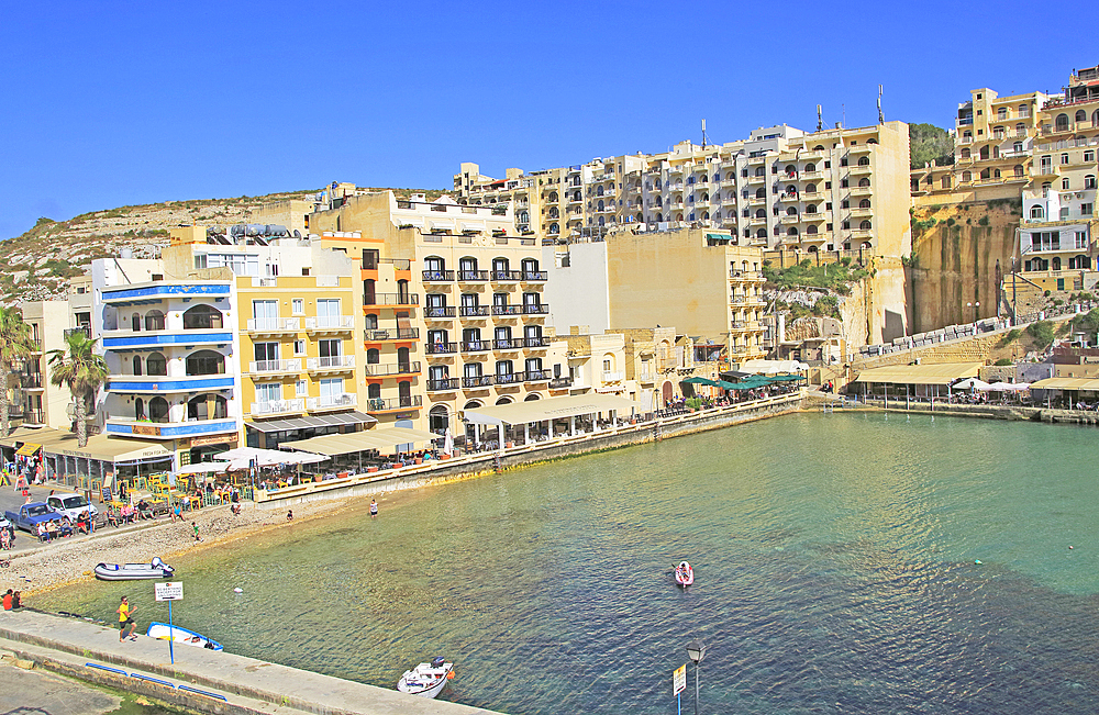 Waterfront hotel buildings, beach and sea at Xlendi, island of Gozo, Malta, Mediterranean, Europe