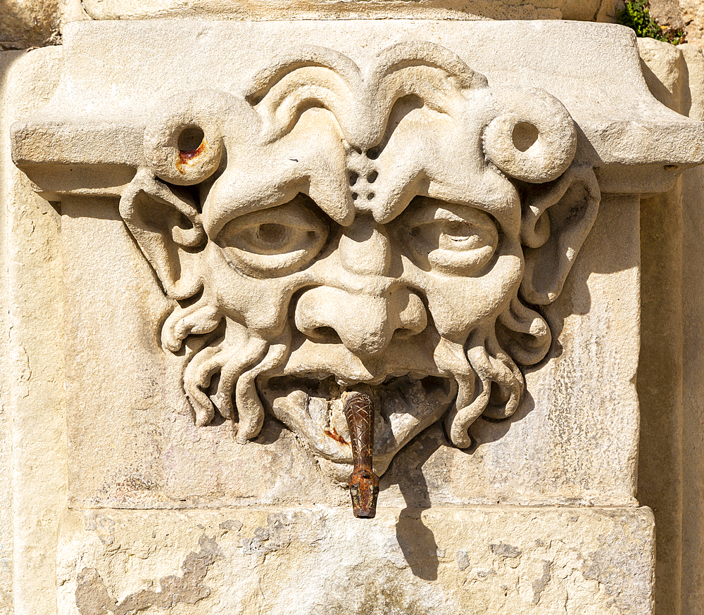 Carved stone face with snake spout emerging from mouth, on old fountain in Cuenca, Castille La Mancha, Spain, Europe