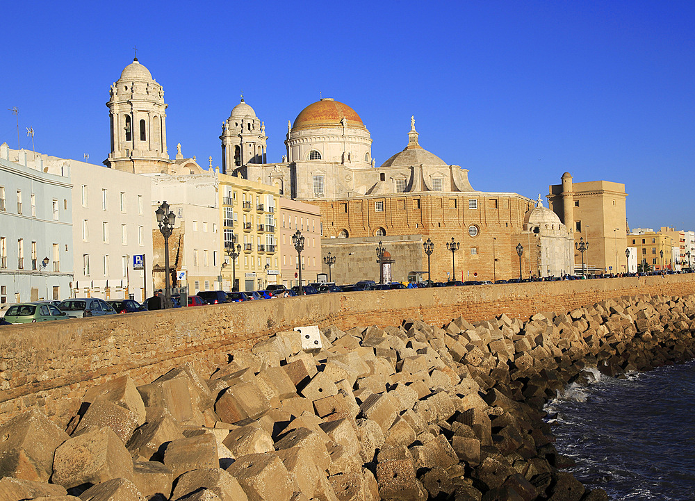 Coastal view east of rock armour coastal defences and cathedral, Cadiz, Spain