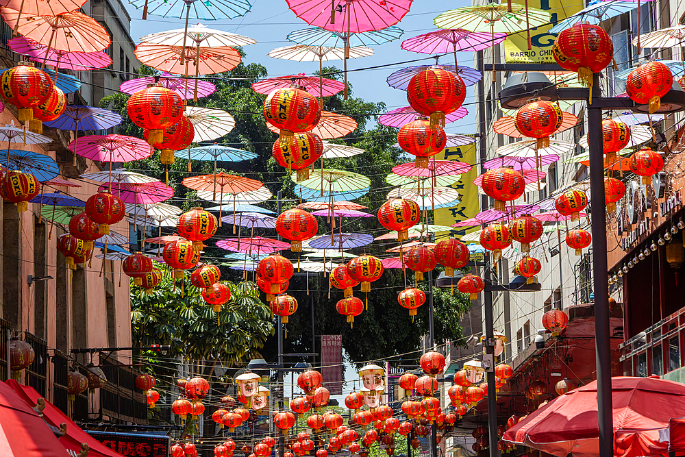 Red paper Chinese lanterns and umbrellas advertising various restaurants, hanging above the street in Chinatown, Mexico City, Mexico, North America