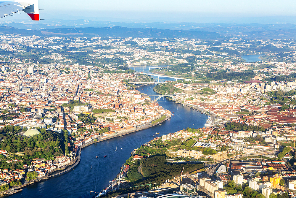 Oblique aerial view from plane window over city of Porto, Portugal, Europe tip of aircraft wing visible