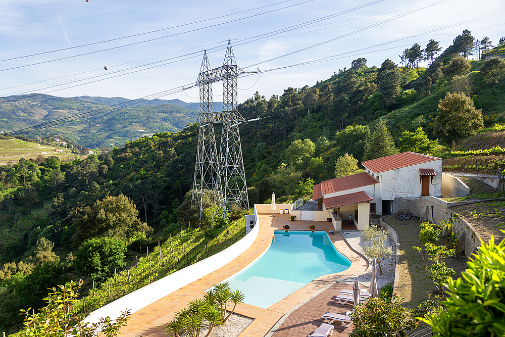 Electricity pylons crossing countryside over swimming pool, Tresouras, near Mesão Frio, River Douro valley, Portugal, Europe
