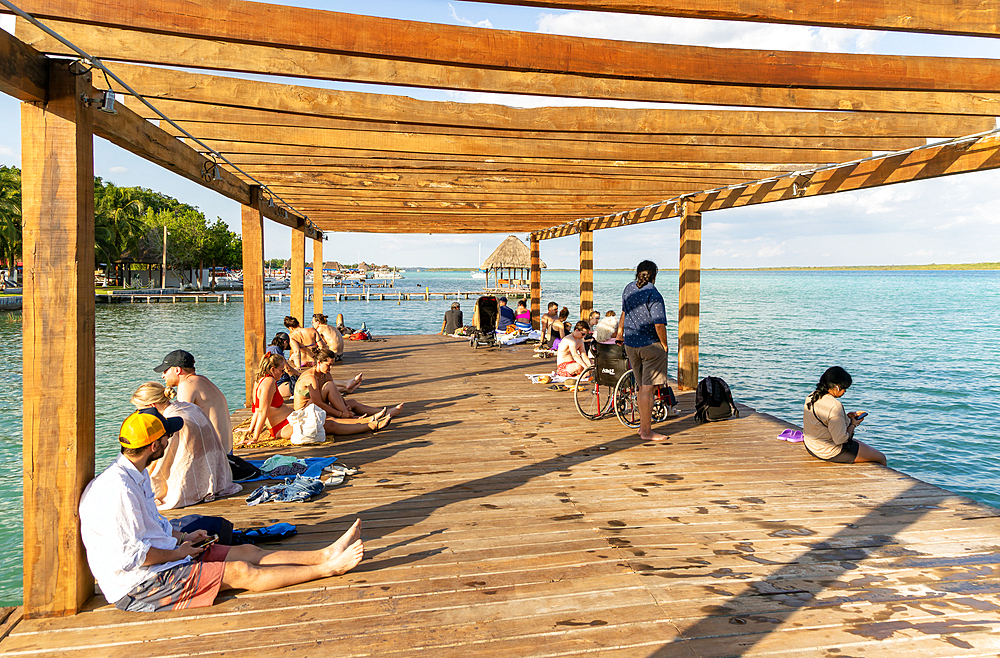 People sitting on woooden jetty pier by waterside, Lake Bacalar, Bacalar, Quintana Roo, Yucatan Peninsula, Mexico, North America