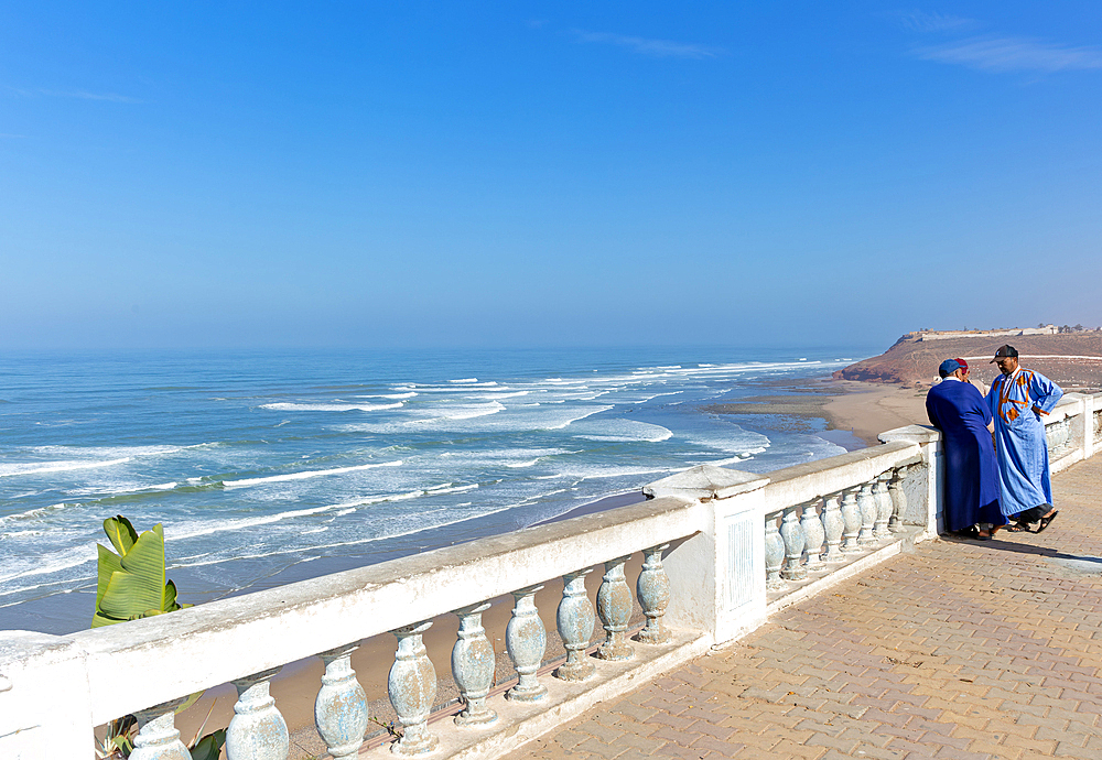 Moroccan men on coastal balustrade next to Atlantic Ocean, Sidi Ifni, Morocco, North Africa, Africa