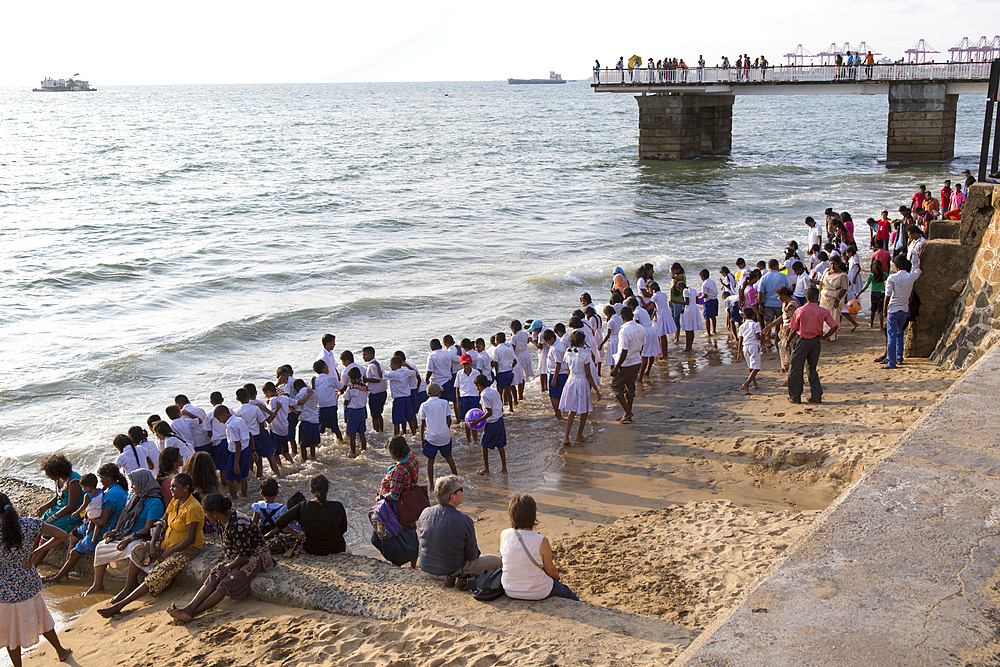 School children paddle in the sea on small sandy beach at Galle Face Green, Colombo, Sri Lanka, Asia