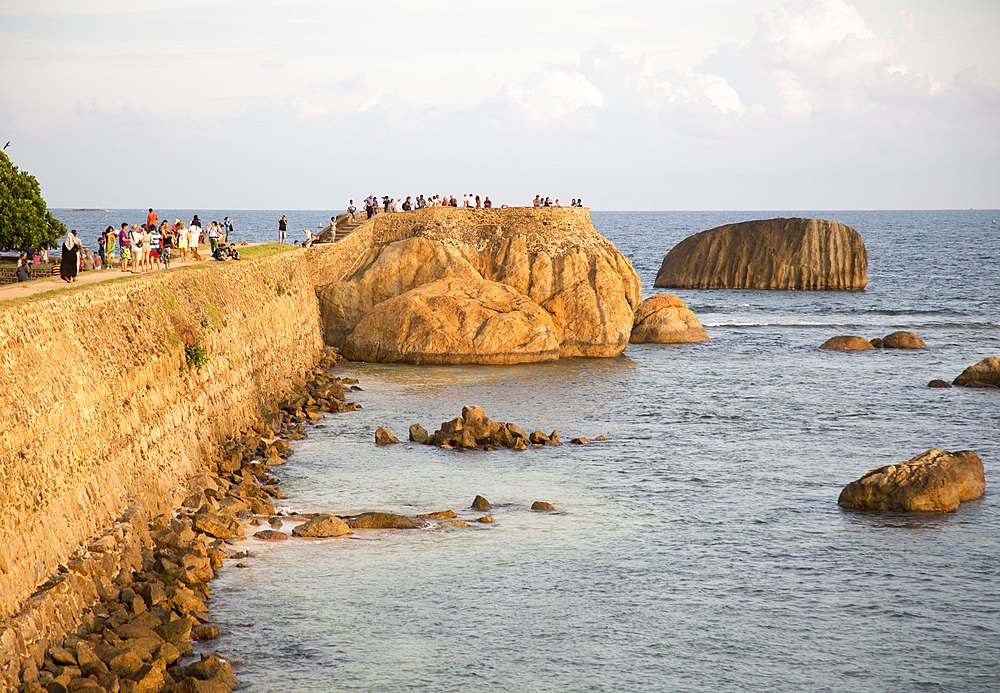 Tourists walk on fort ramparts in historic town of Galle, UNESCO World Heritage Site, Sri Lanka, Asia