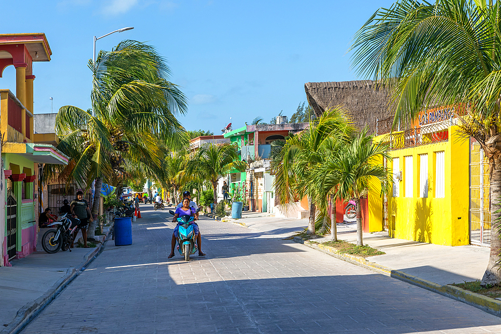 Palm trees, motorcycles and colourful buildings on quiet village road, Celestun, Yucatan, Mexico, North America