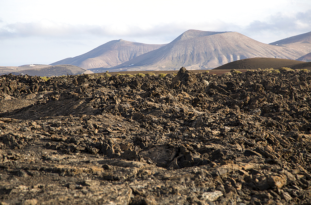 Volcanic landscape of solidified lava flows and distant cone volcanoes, near Yaiza, Lanzarote, Canary Islands, Spain, Atlantic, Europe